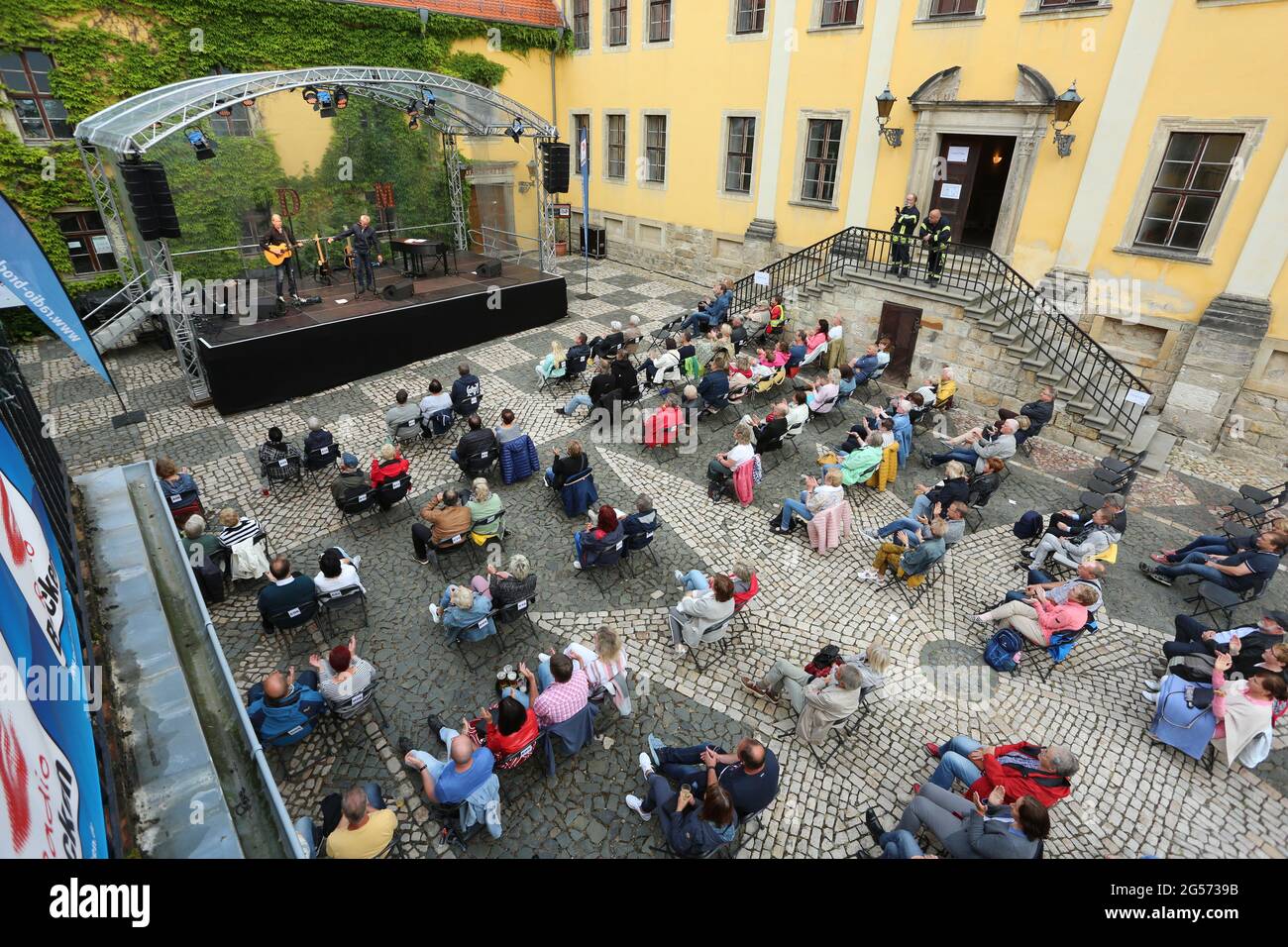 Ballenstedt, Allemagne. 25 juin 2021. 25 juin 2021, Saxe-Anhalt, Ballenstedt: Les concertgoers s'assoient dans la cour de l'ensemble du château. Avec la nouvelle série de concerts 'Schlosstheater Open Air', la culture revient au Harz pour la première fois depuis le verrouillage. C'est la première fois que des événements culturels se déroulent dans la région de Harz, à côté de Magdeburg et de Halle. Le chanteur Dirk Michaelis a présenté des chansons anciennes et nouvelles bien connues lors de son premier concert après le Lockdown. Les organisateurs de la série de concerts dans le château présentent des artistes comme la chanteuse Toni Krahl, Dieter Bier ou aussi l'acteur SK Banque D'Images