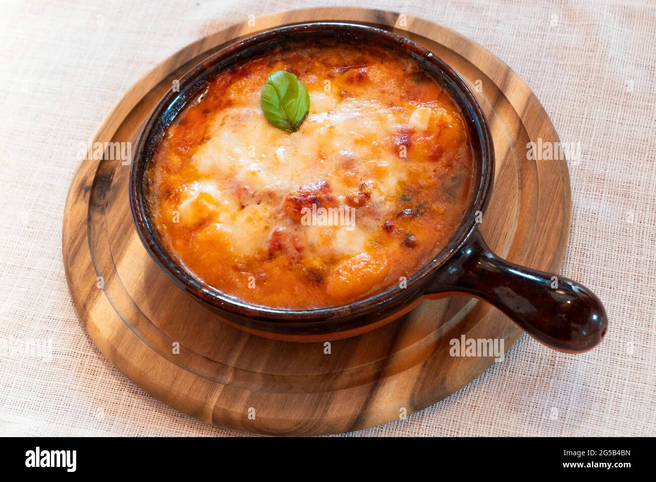 Gnocchi alla Sorrentina, boulettes de pommes de terre italiennes à la sauce tomate, gratinées avec du fromage mozzarella dans un plat en terre cuite Banque D'Images