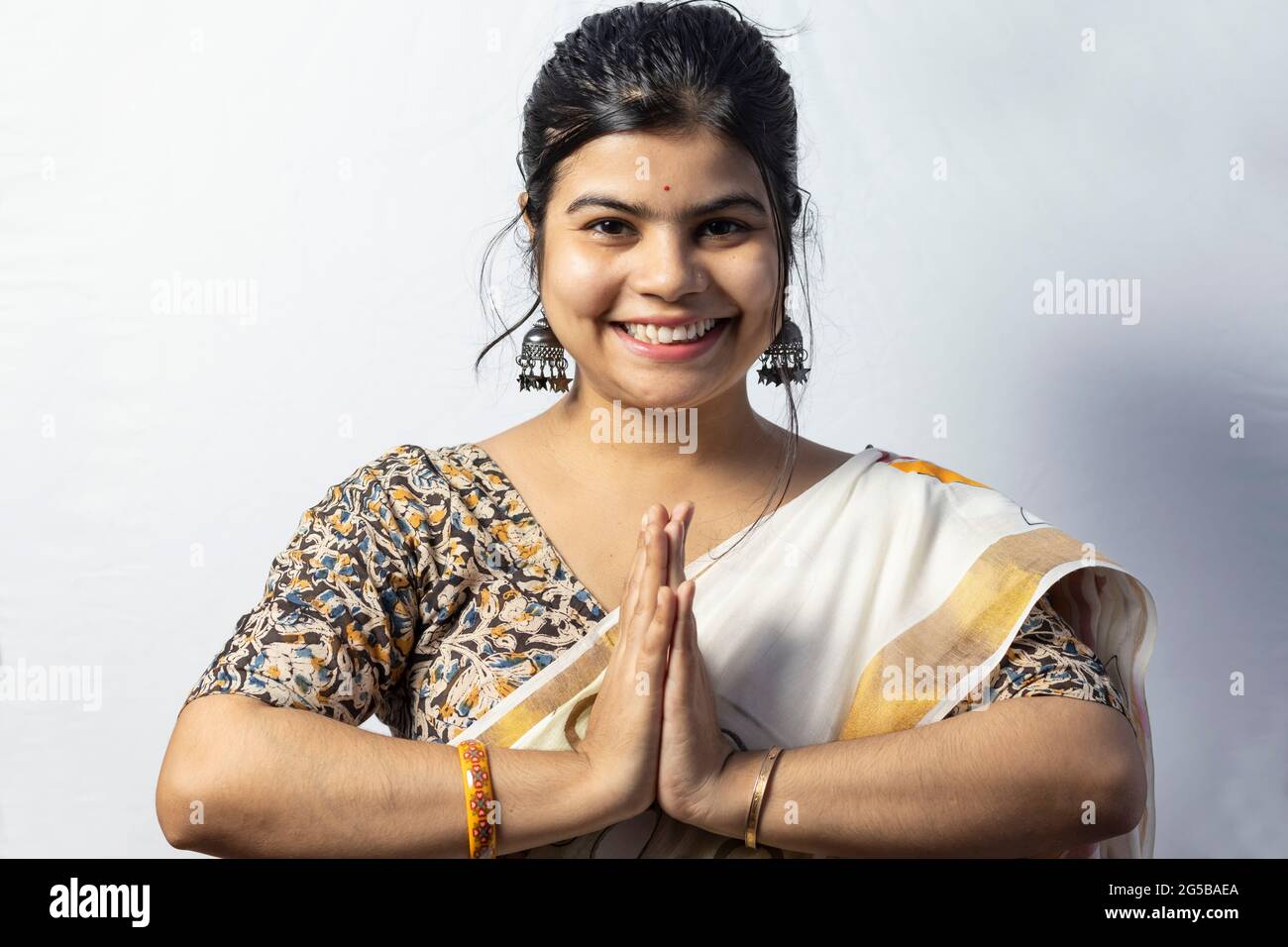 Une belle femme indienne en saree isolée sur fond blanc accueille dans une posture namaste avec visage souriant Banque D'Images