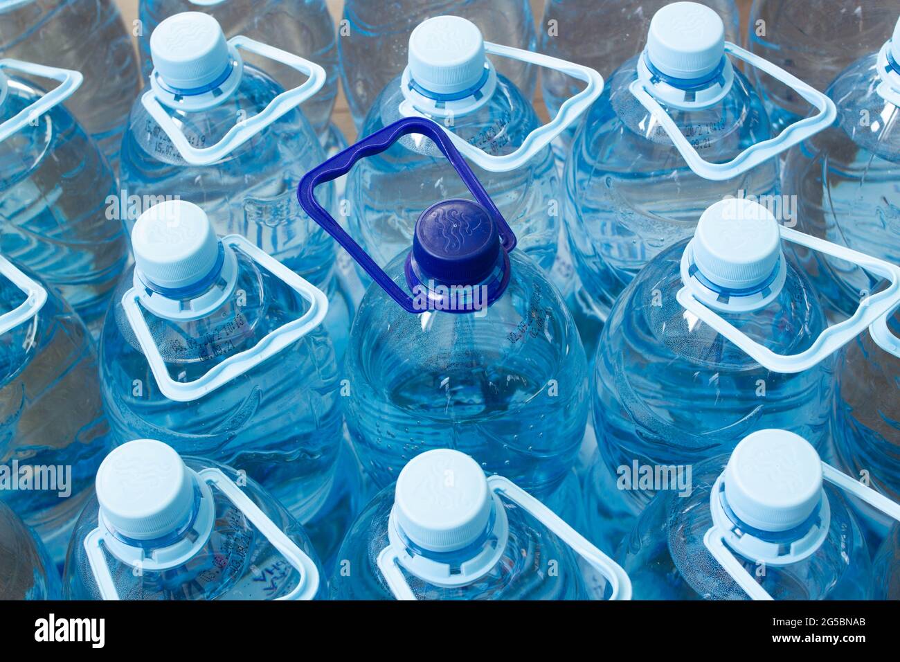 De nombreuses bouteilles en plastique bleu avec bouchons bleus et une avec  bouchon bleu foncé avec eau minérale claire dans un supermarché. Eau pure,  filtrée et écologique Photo Stock - Alamy