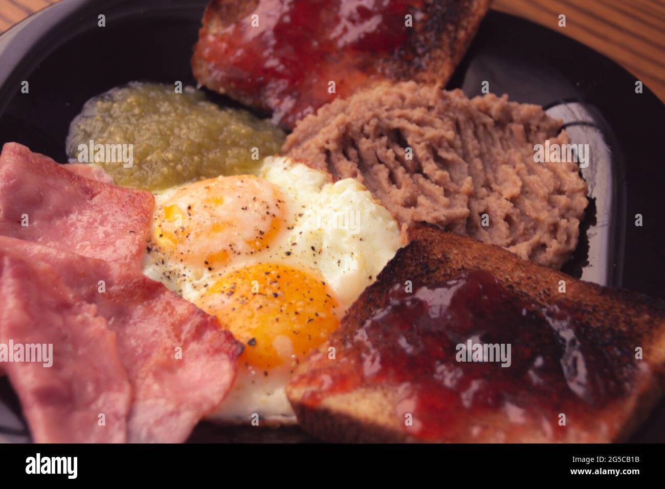 Photographie d'une paire d'oeufs frits avec des haricots, de la confiture et du pain avec de la confiture Banque D'Images
