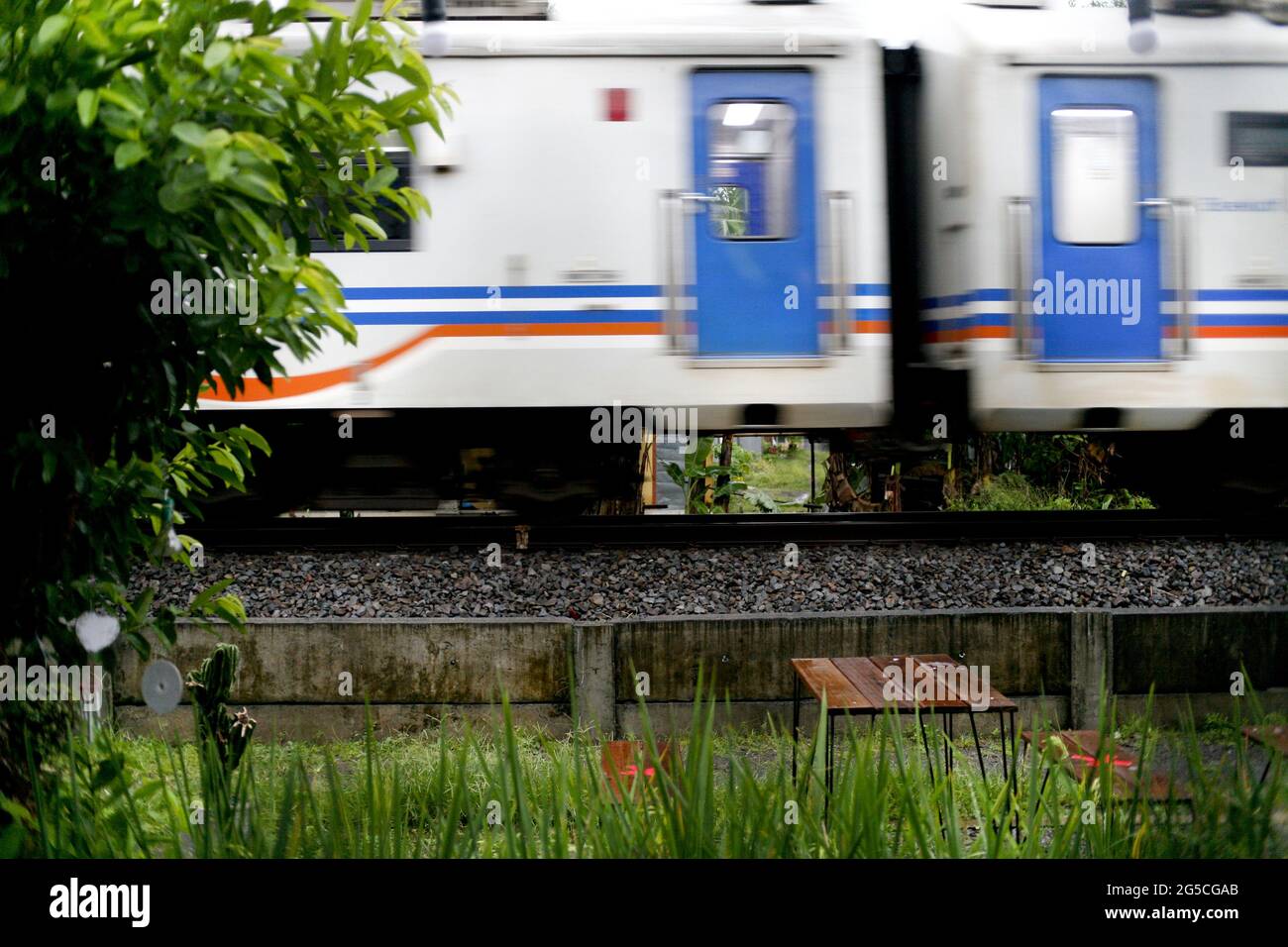 Train blanc et bleu passant près d'une cour Banque D'Images