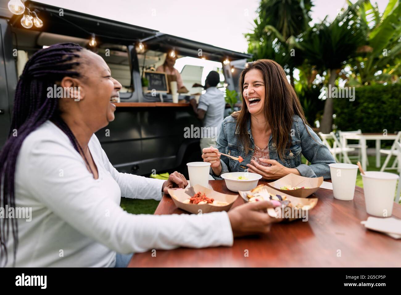 Heureux multiracial senior amis ayant plaisir à manger dans un camion de nourriture de rue Banque D'Images