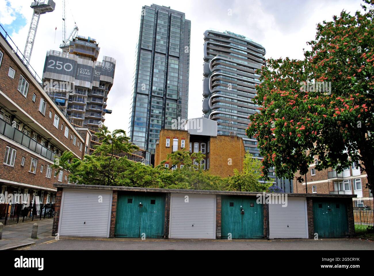 GARAGES DE FAIBLE HAUTEUR ET APPARTEMENTS DE CONSEIL AVEC DE NOUVELLES CONSTRUCTIONS DE LA VIEILLE RUE QUI LES DOMINENT. Banque D'Images