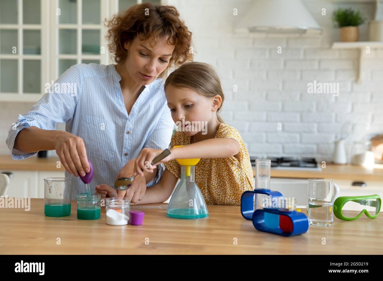Une jeune mère attentionnée enseignant une petite fille faisant des expériences de chimie. Banque D'Images