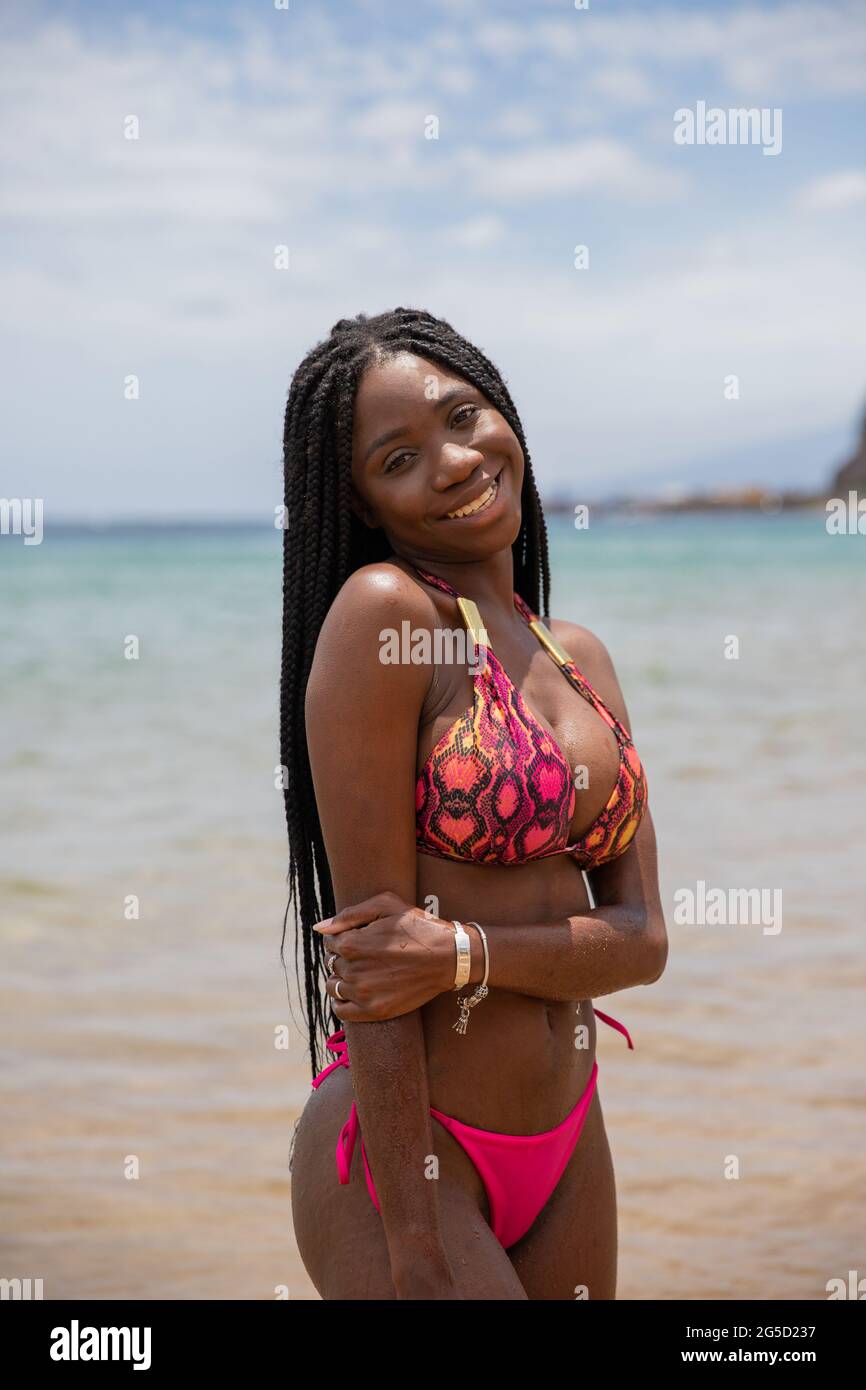 Belle fille africaine près de la plage souriante, elle a de longues tresses  et porte un bikini Photo Stock - Alamy