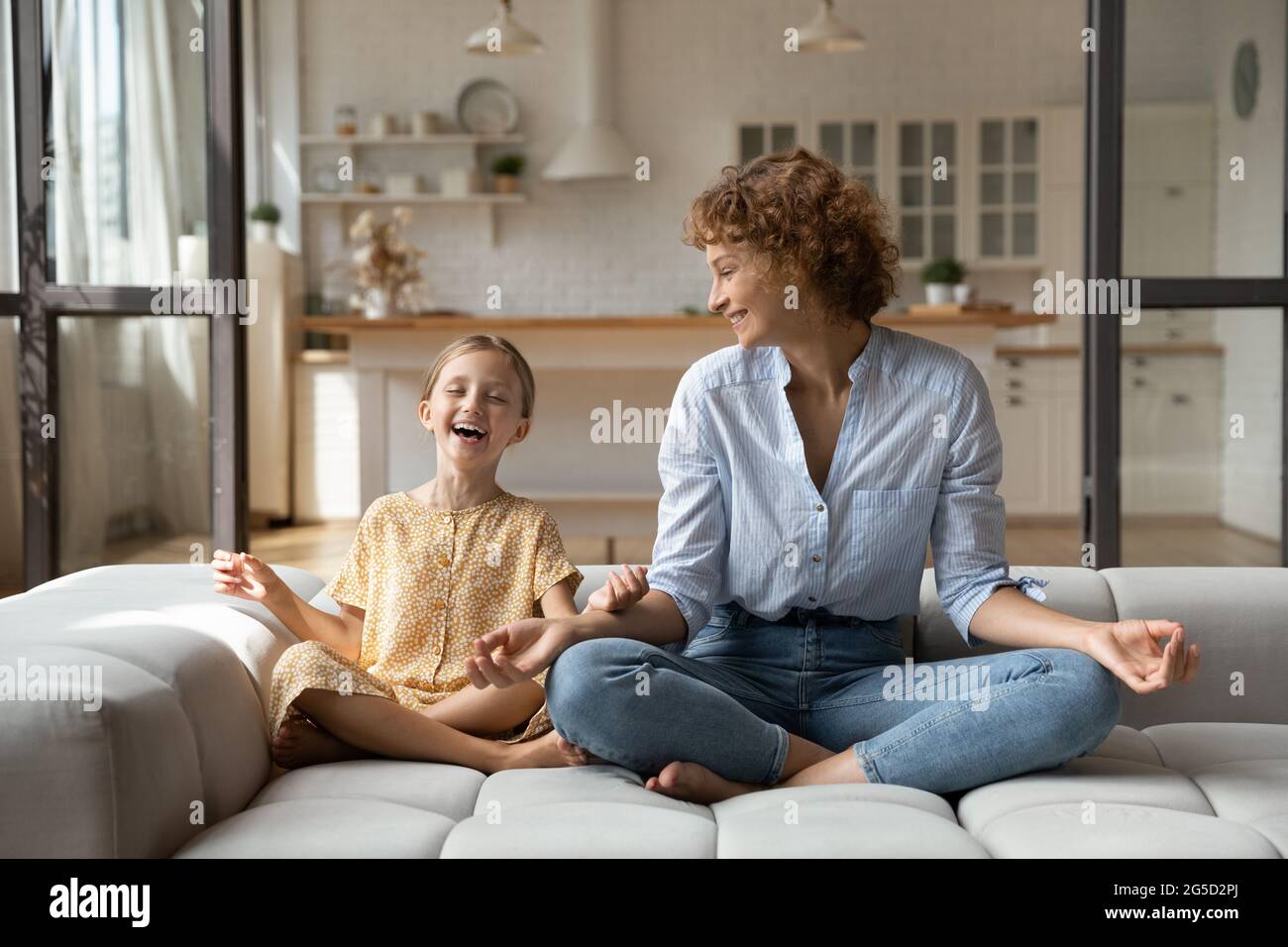 Bonne petite fille méditant avec la mère à la maison. Banque D'Images