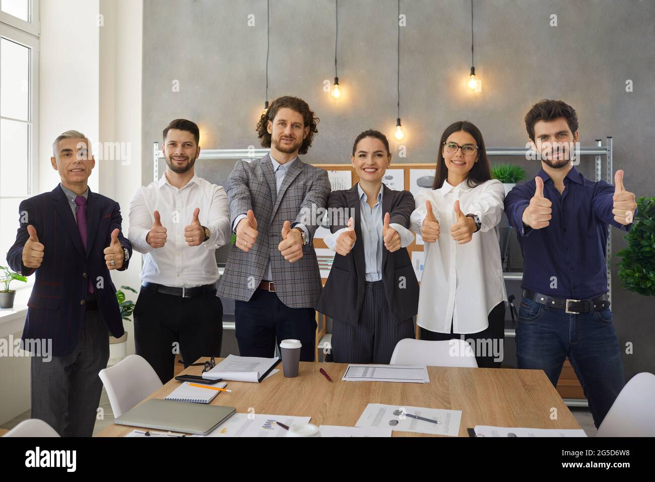 Une équipe d'employés heureux de l'entreprise qui se sont fait un pouce après une réunion d'affaires réussie Banque D'Images