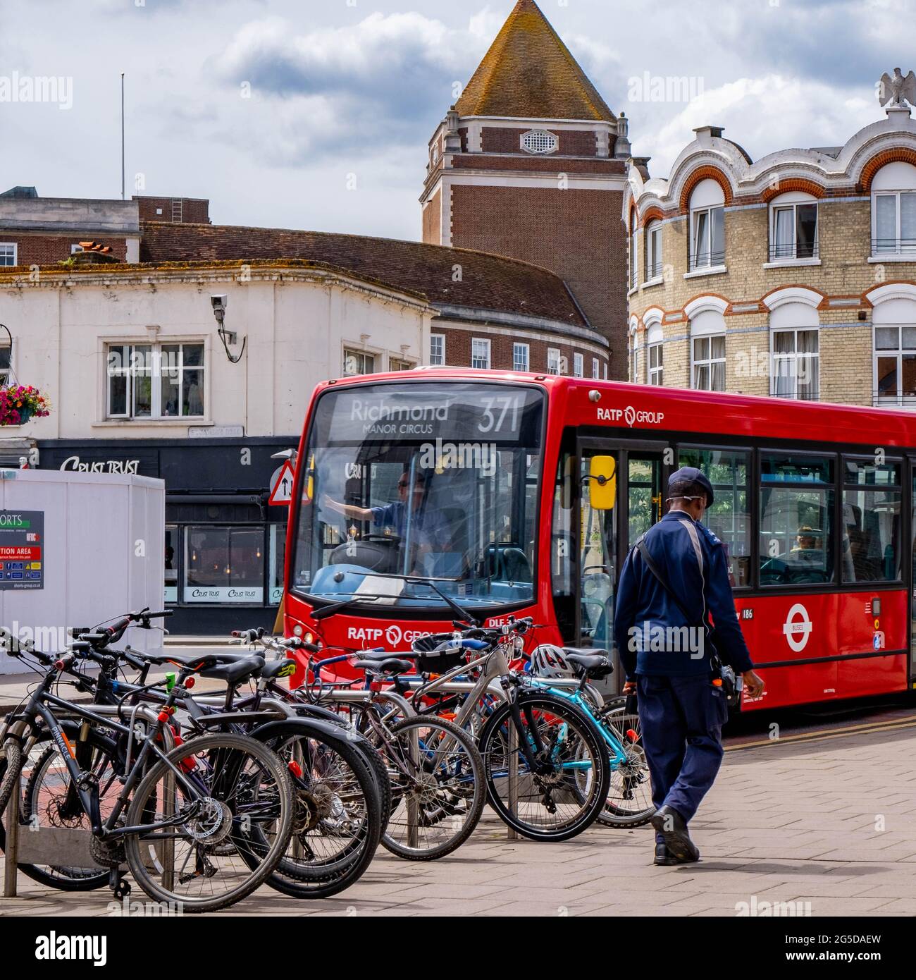 Kingston London, Royaume-Uni, juin 26 2021, Homme passant devant UNE rangée de bicyclettes garées et UN bus de transport public à un seul Decker Red Banque D'Images