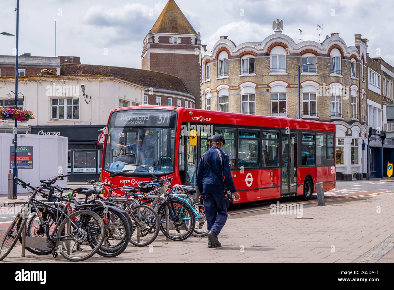 Kingston London, Royaume-Uni, juin 26 2021, Homme passant devant UNE rangée de bicyclettes garées et UN bus de transport public à un seul Decker Red Banque D'Images