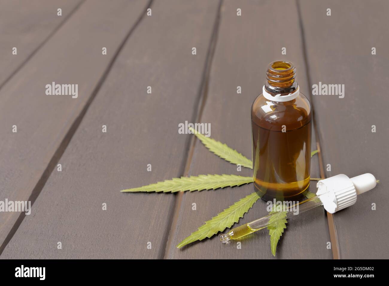Huile de CBD dans une bouteille de verre avec feuille de marijuana verte sur fond de bois avec espace de copie Banque D'Images