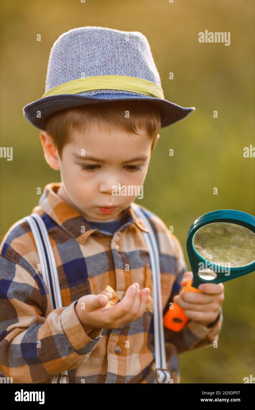 petit garçon explorant la nature dans la prairie avec une loupe Banque D'Images