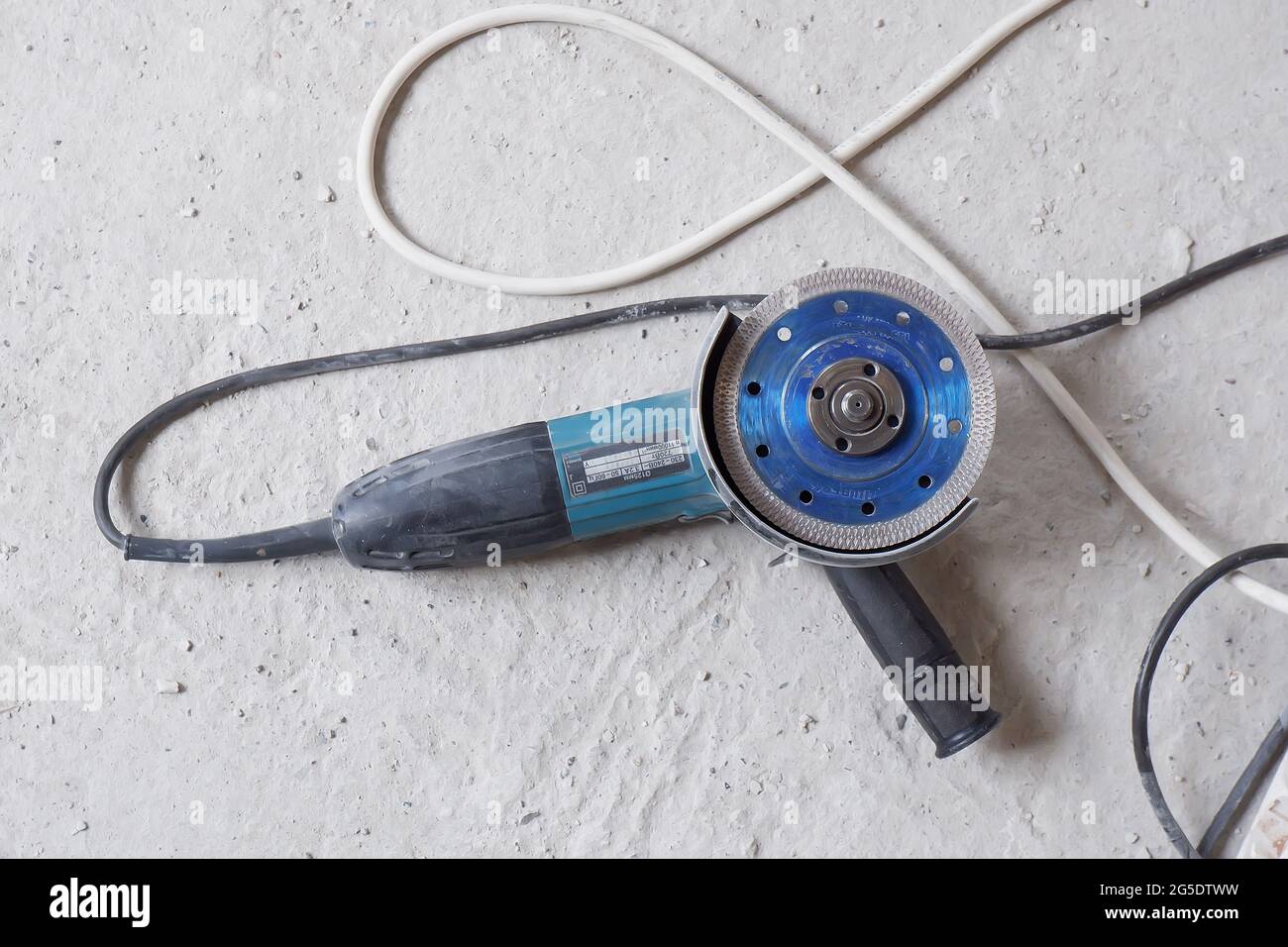 La machine de meulage d'angle repose après avoir travaillé avec des matériaux de construction sur le sol en béton, Banque D'Images