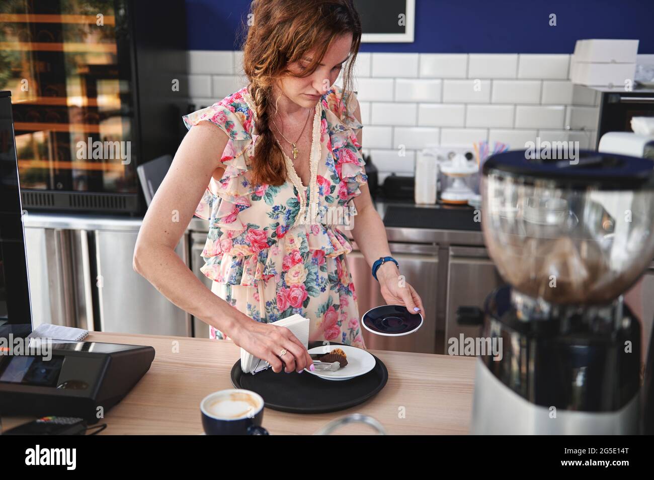 La jeune femme, barista, entrepreneur se concentre sur le service derrière un comptoir de bar dans un café, mettant des truffes sur une assiette Banque D'Images