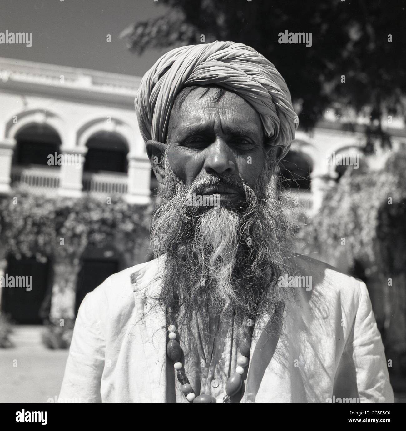 1950s, historique, un commerçant de rue indien, avec la longue barbe et le turban, Benares, Inde. Banque D'Images