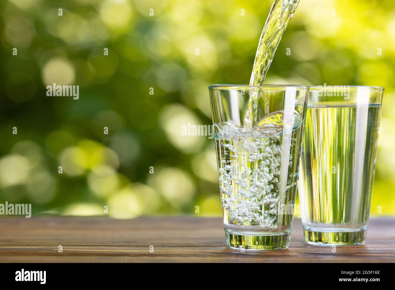 l'eau coule dans le verre sur la table à l'extérieur Banque D'Images
