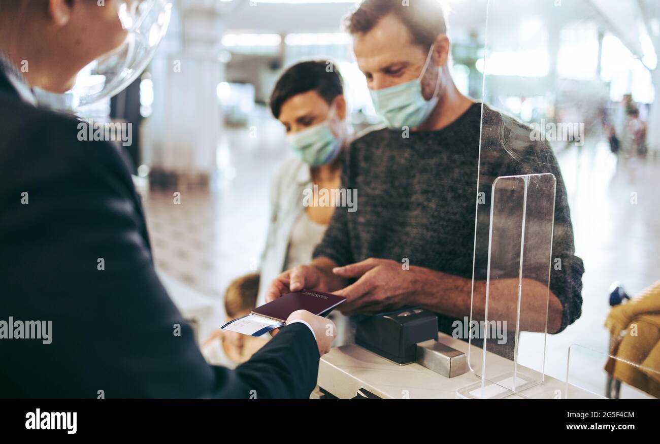 voyageur donnant passeport au comptoir d'enregistrement à l'aéroport pendant la pandémie. Homme debout au comptoir d'enregistrement à l'aéroport. Banque D'Images