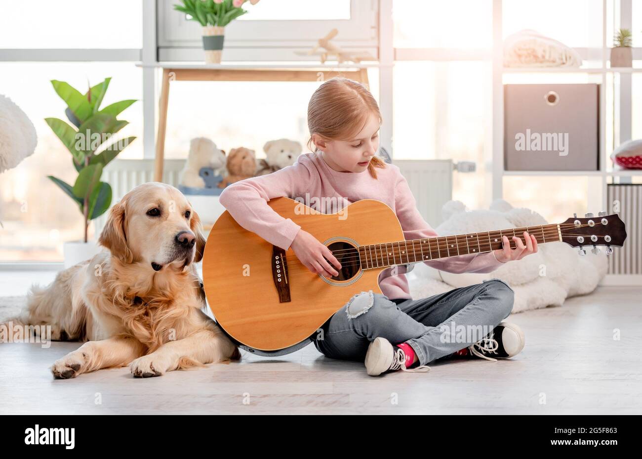 Petite fille avec guitare et chien Golden Retriever Banque D'Images