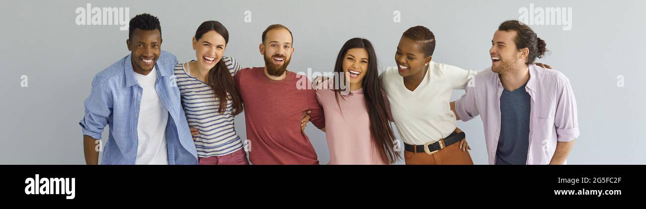 Groupe diversifié de jeunes amis heureux debout ensemble sur fond de studio Banque D'Images