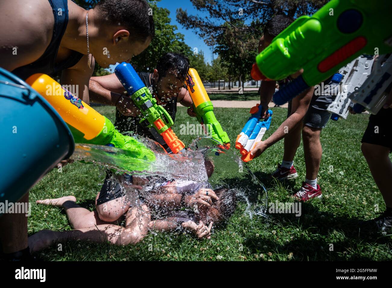 Madrid, Espagne. 27 juin 2021. Un jeune homme reçoit un seau plein d'eau alors qu'il participe à un combat d'eau d'été dans le quartier de Vicalvaro à Madrid. Credit: Marcos del Mazo/Alay Live News Banque D'Images