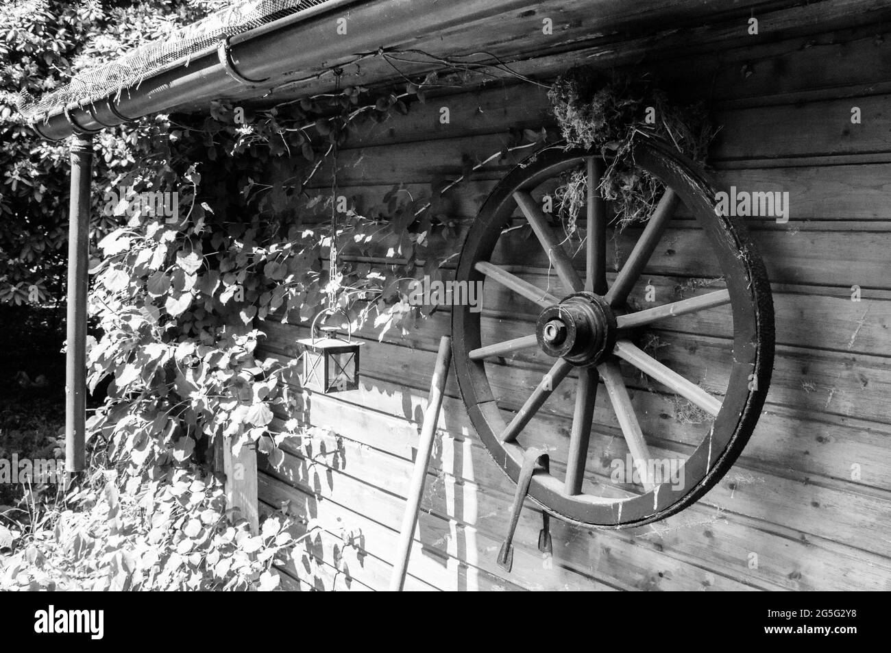 Décoration sur un abri de jardin. Une ancienne roue de chariot sur laquelle un oiseau a construit son nid Banque D'Images