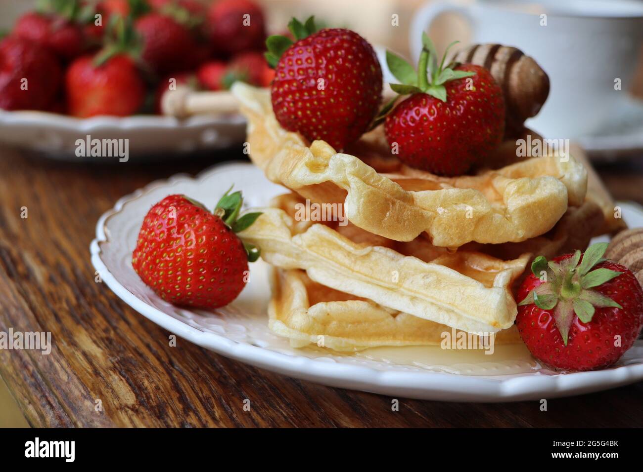 Gaufres belges avec baies fraîches, fraises, miel et cappuccino pour le petit déjeuner Banque D'Images