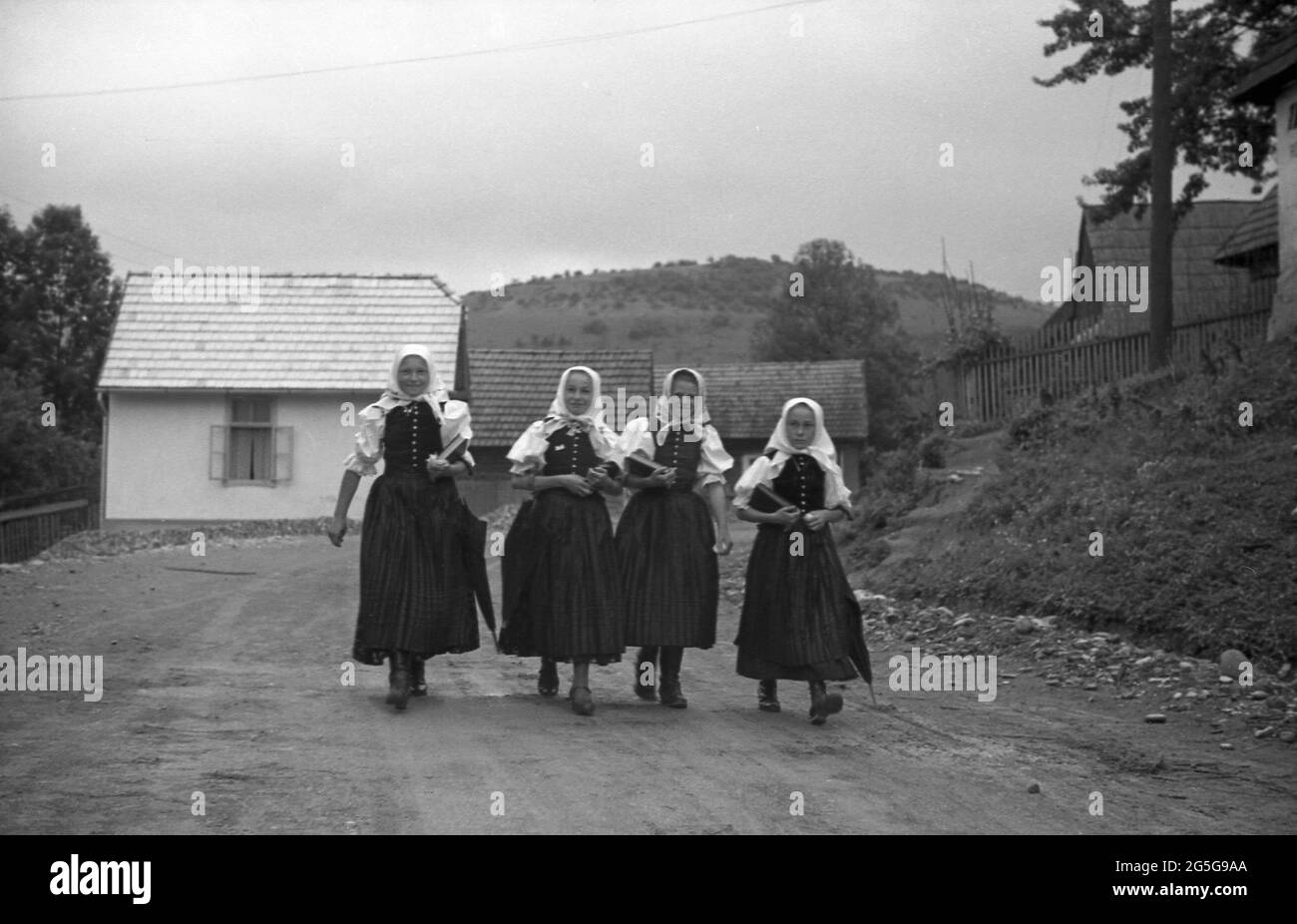 1930s, historique, village de Bohême, quatre écolières tchèques en costume traditionnel marchant le long d'une route de village rural. Cette région de la Tchécoslovaquie était connue et surnommée à cette époque les Sudètes, nom historique du peuple allemand des sudètes vivant dans les pays de Bohême occidentale et d'autres régions frontalières. Banque D'Images