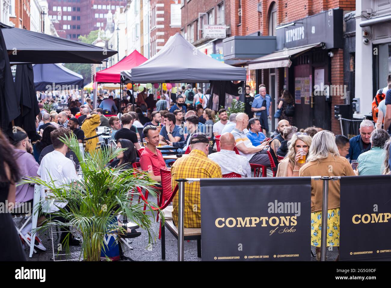 Les clients apprécient de prendre un verre sur une terrasse temporaire socialement distancée dans une rue fermée Banque D'Images