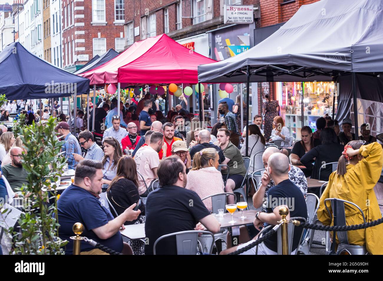 Les clients apprécient de prendre un verre sur une terrasse temporaire socialement distancée dans une rue fermée Banque D'Images