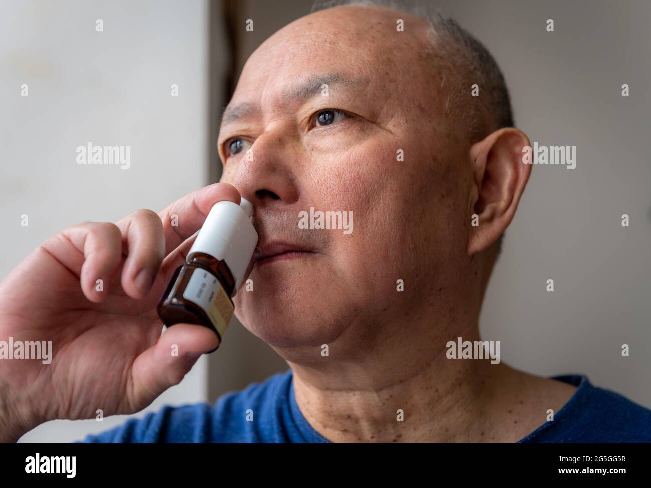 Un homme mûr souffrant de fièvre hayfièvre appliquant un spray nasal pour le soulagement des symtomes Banque D'Images