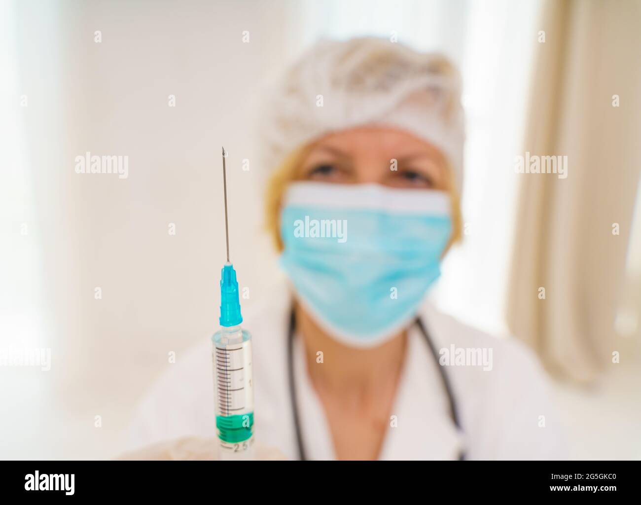 Le médecin avec un masque et une seringue est prêt à administrer le vaccin contre le covid 19 Banque D'Images