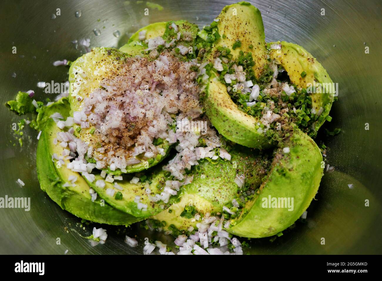 écrasées d'avocats avec des oignons et des herbes hachés, assaisonnements de sel et de poivre Banque D'Images
