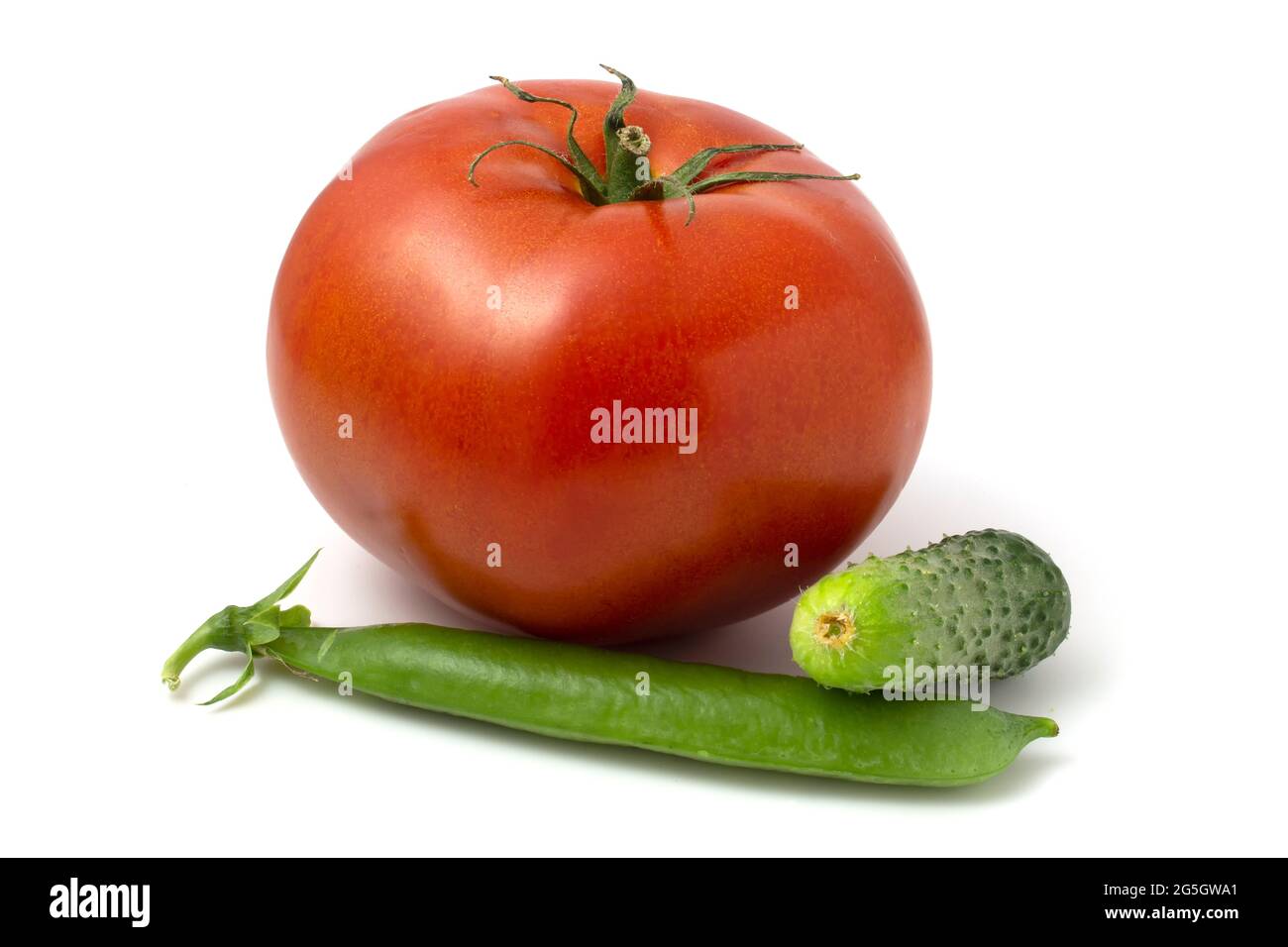 Une grande tomate, un petit concombre et une gousse de petits pois verts. Légumes frais isolés sur fond blanc Banque D'Images