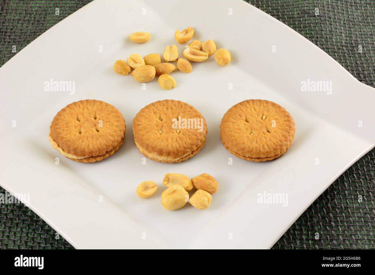 Biscuits sandwich à la crème d'arachide avec arachides sur une assiette à collation blanche Banque D'Images