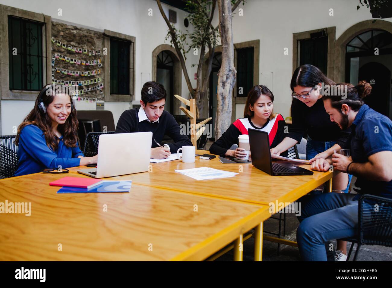 Groupe de jeunes gens d'affaires latins occupés à travailler sur le projet à l'extérieur du bureau au Mexique Banque D'Images Groupe de jeunes gens d'affaires latins occupés à travailler sur le projet à l'extérieur du bureau au Mexique Banque D'Images