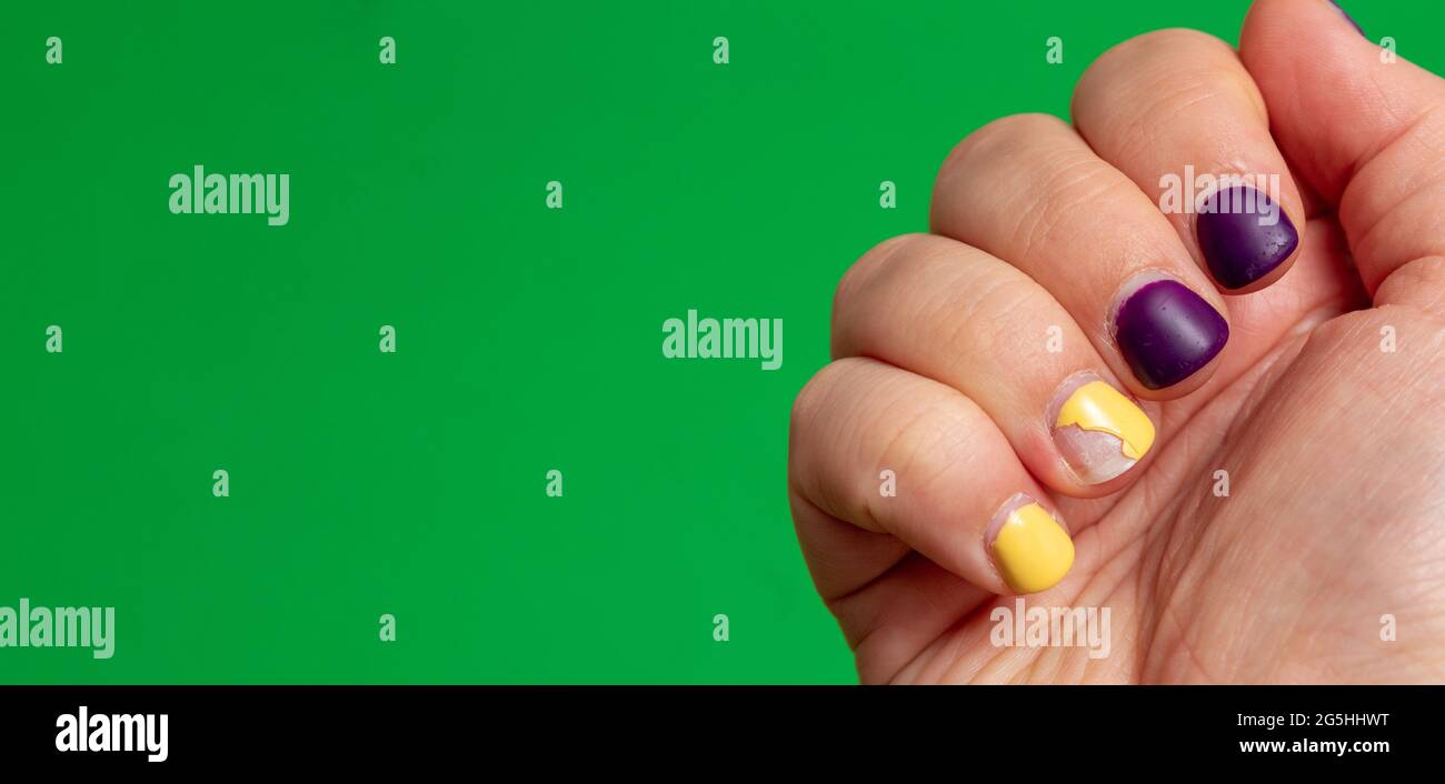 Les ongles sur la main avec vernis à ongles endommagé sont violets et  jaunes. Arrière-plan vert avec espace pour le texte. Mise au point  sélective Photo Stock - Alamy