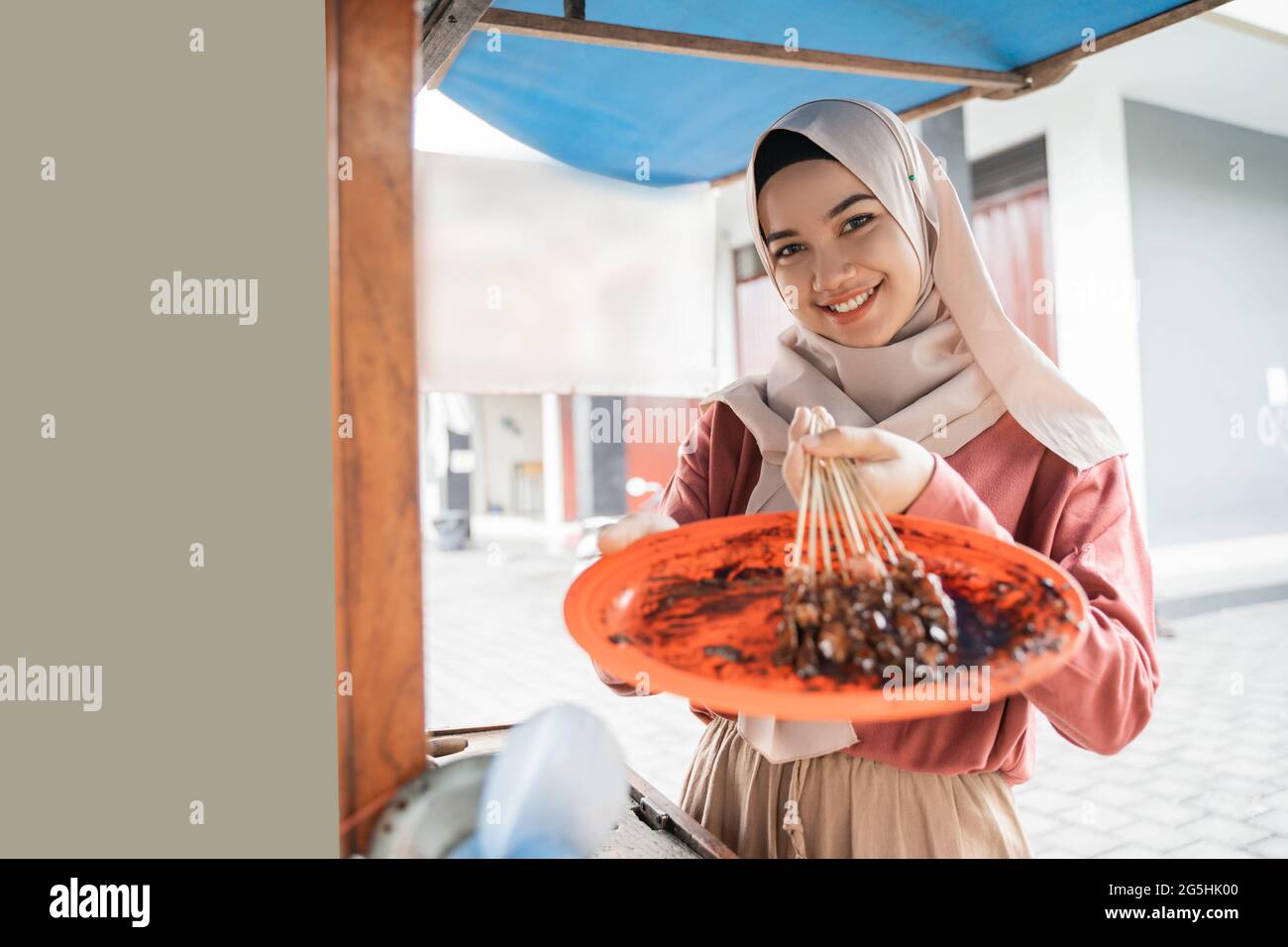 femme asiatique musulmane vendant du poulet satay sur son chariot alimentaire Banque D'Images