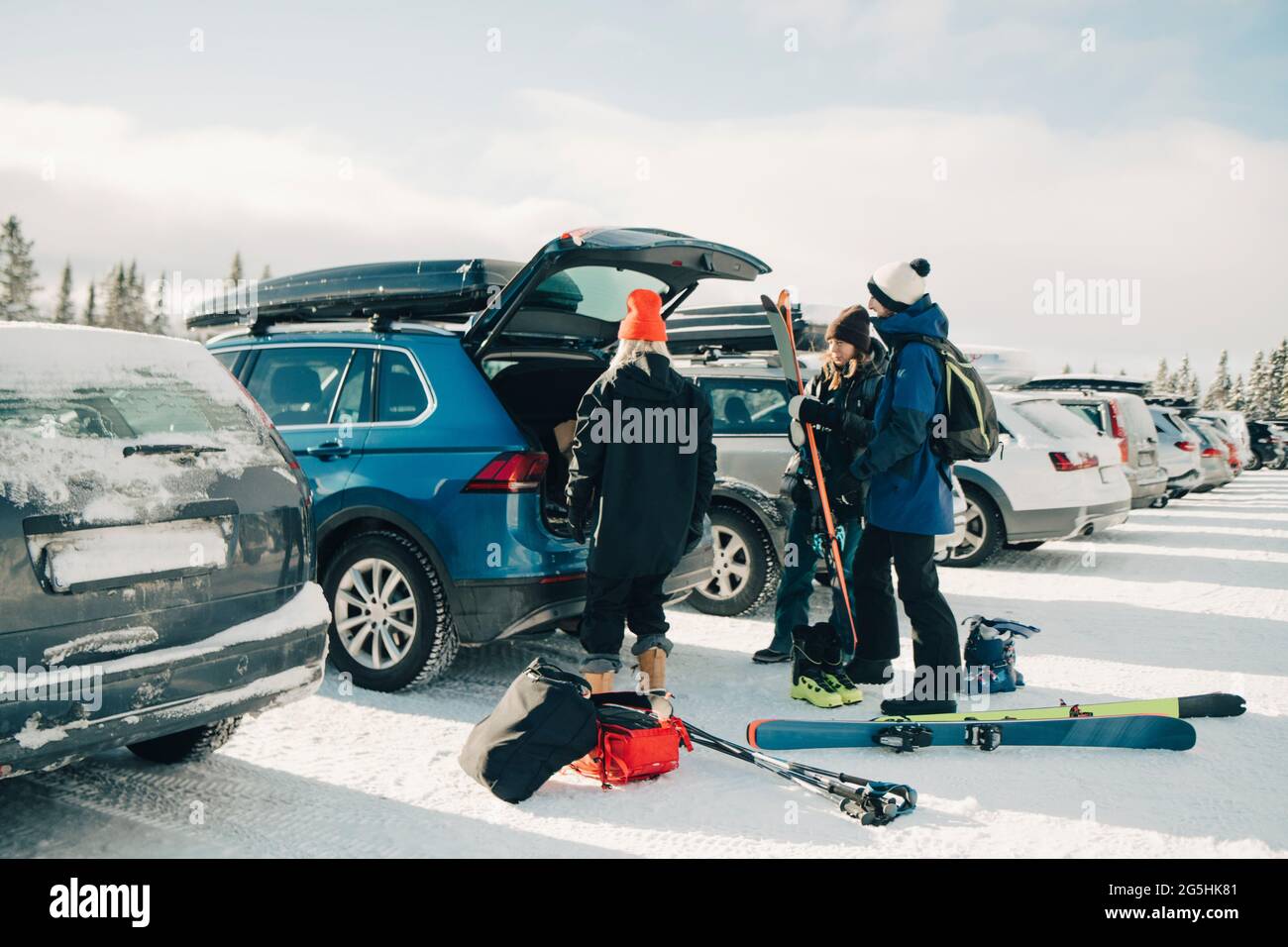 Des amis de sexe féminin et masculin chargent des skis dans le wagon-coffre pendant l'hiver Banque D'Images