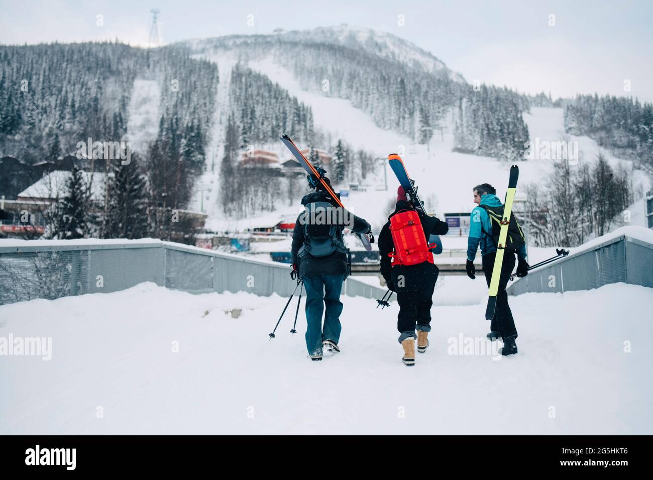 Vue arrière de femmes et amis de sexe masculin marchant sur la neige à la station de ski pendant les vacances Banque D'Images