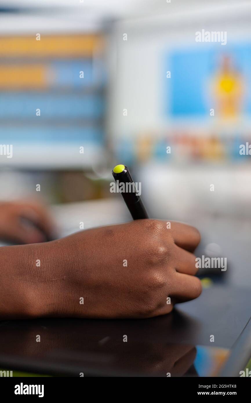 Gros plan de retouche photo africaine tenant un stylet retouche photo de client à l'aide d'un ordinateur avec deux écrans. Black Woman éditeur retouche des ressources dessin sur tablette graphique dans le bureau de création Banque D'Images