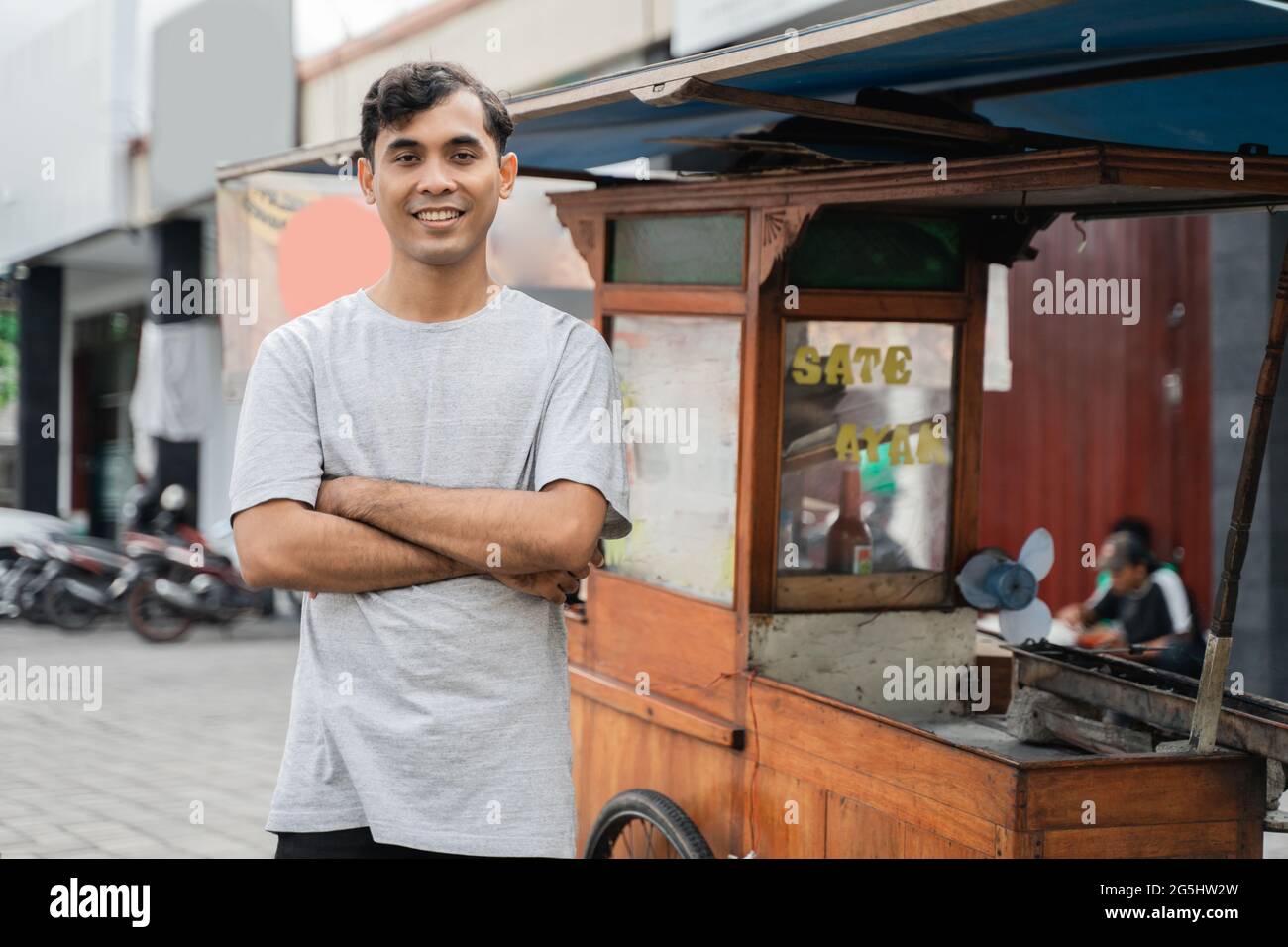 homme rue vendeur de nourriture de poulet satay avec chariot de vente de sate ayam. Banque D'Images