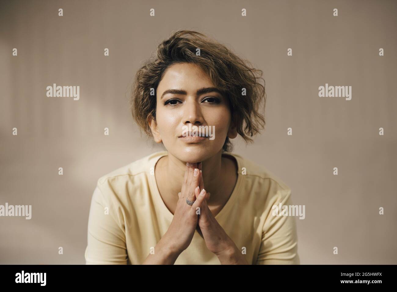 Femme avec les mains classées contre le mur beige Banque D'Images