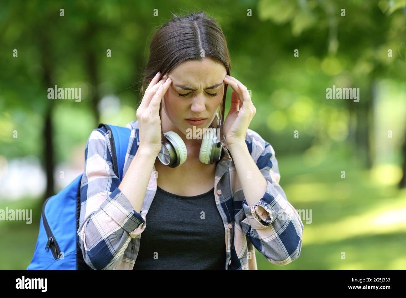 Étudiant souffrant de maux de tête marchant dans un parc ou un campus l'été Banque D'Images