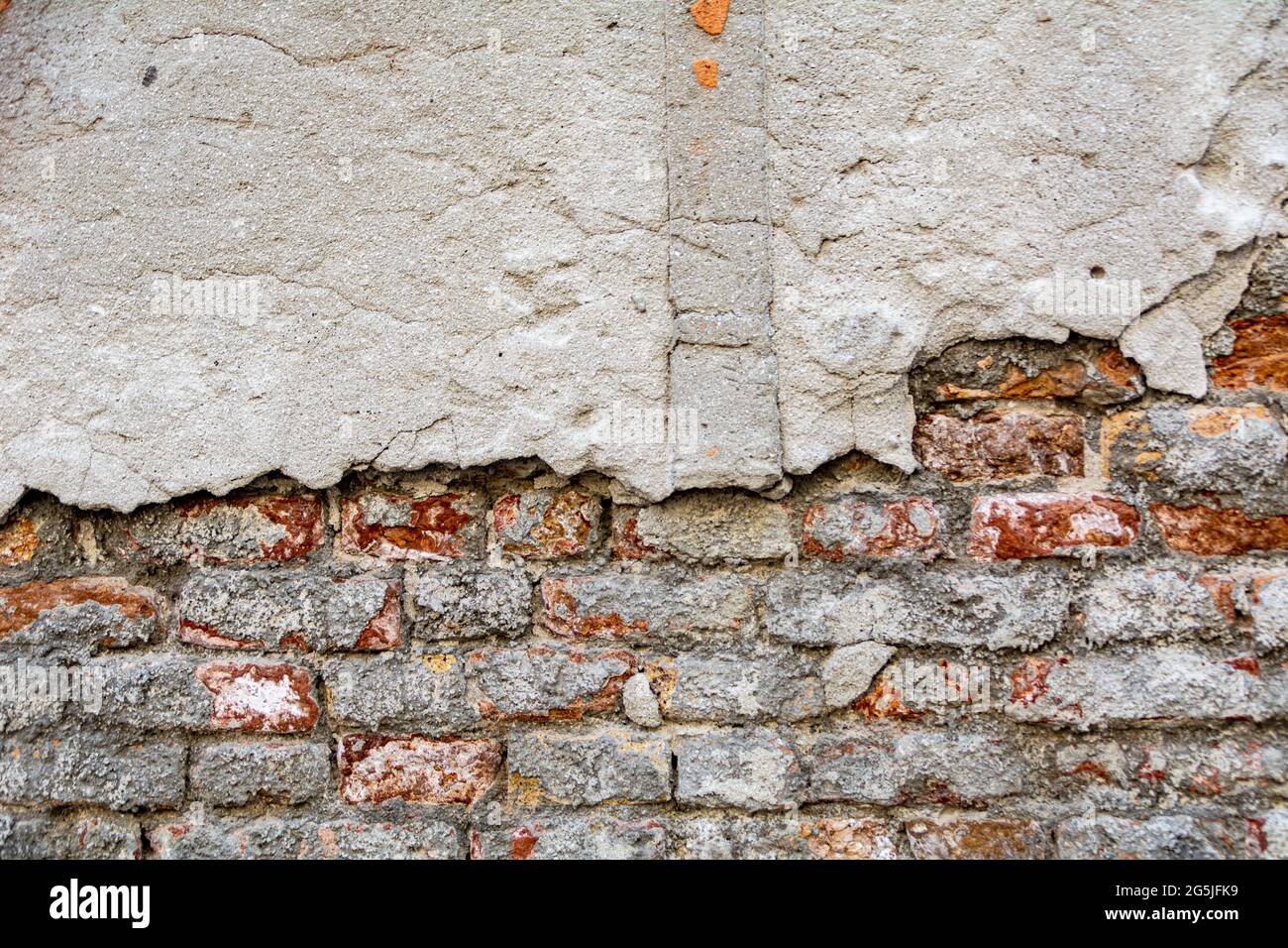 Briques plâtrés avec des morceaux de stuc. Rouge, mur texturé avec une surface endommagée. Arrière-plan ancien et abstrait. Banque D'Images