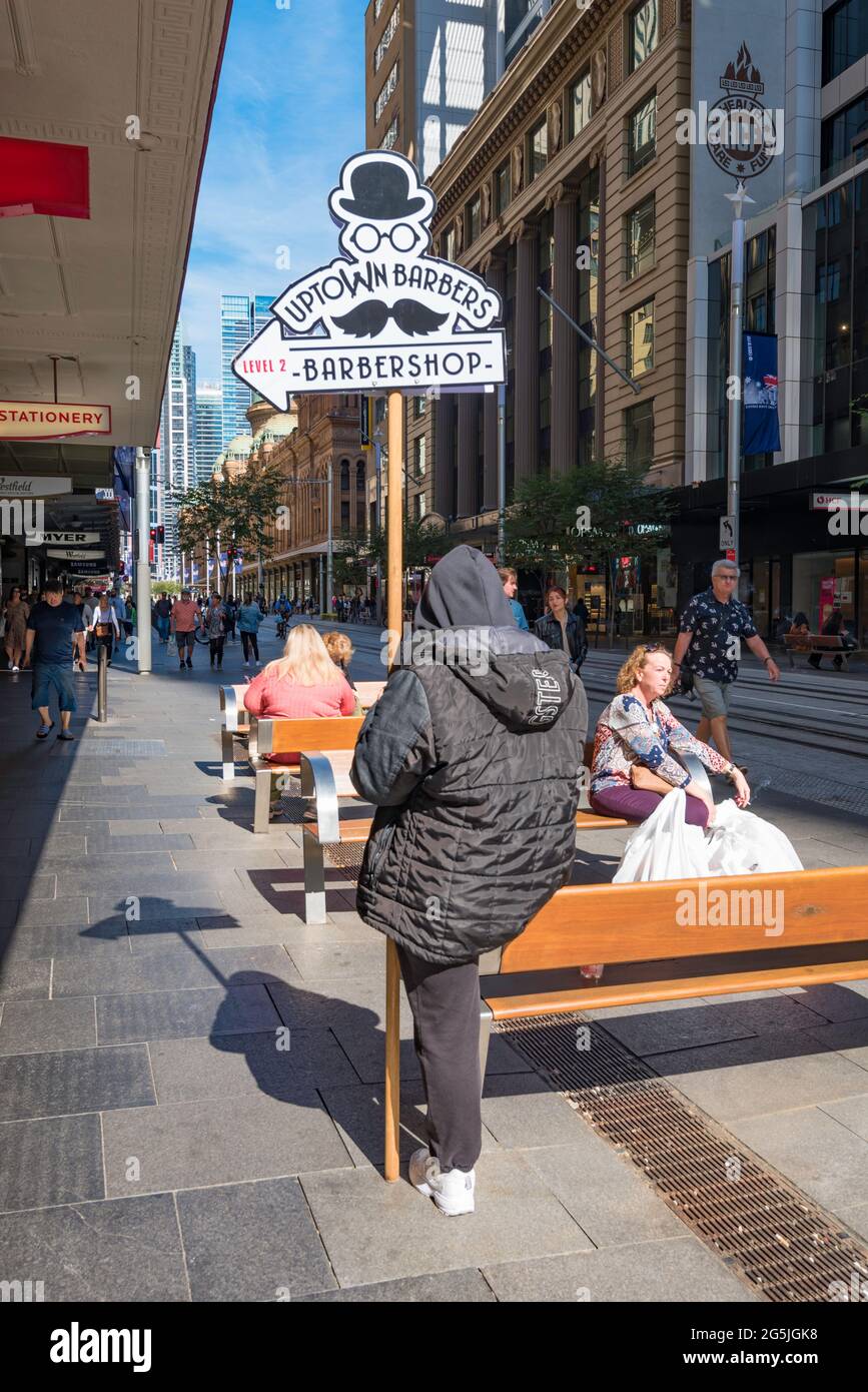 Une personne tenant une bannière ou une publicité pour un barbier coiffeur tout en regardant leur téléphone dans Pitt Street Mall, Sydney, Australie Banque D'Images