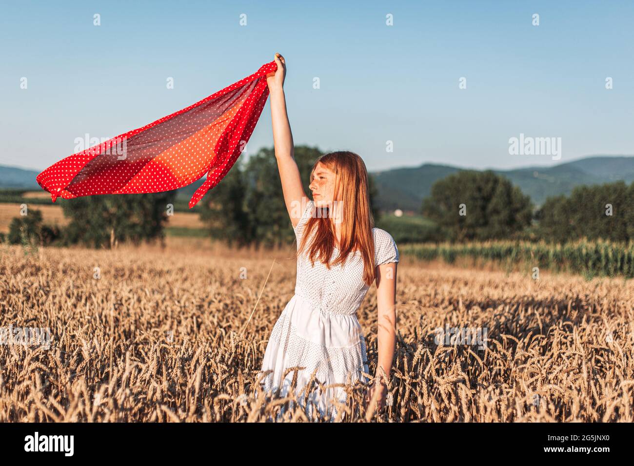Photo à l'extérieur d'une jeune fille au gingembre en robe blanche tenant  un foulard rouge en vol. Copier l'espace Photo Stock - Alamy
