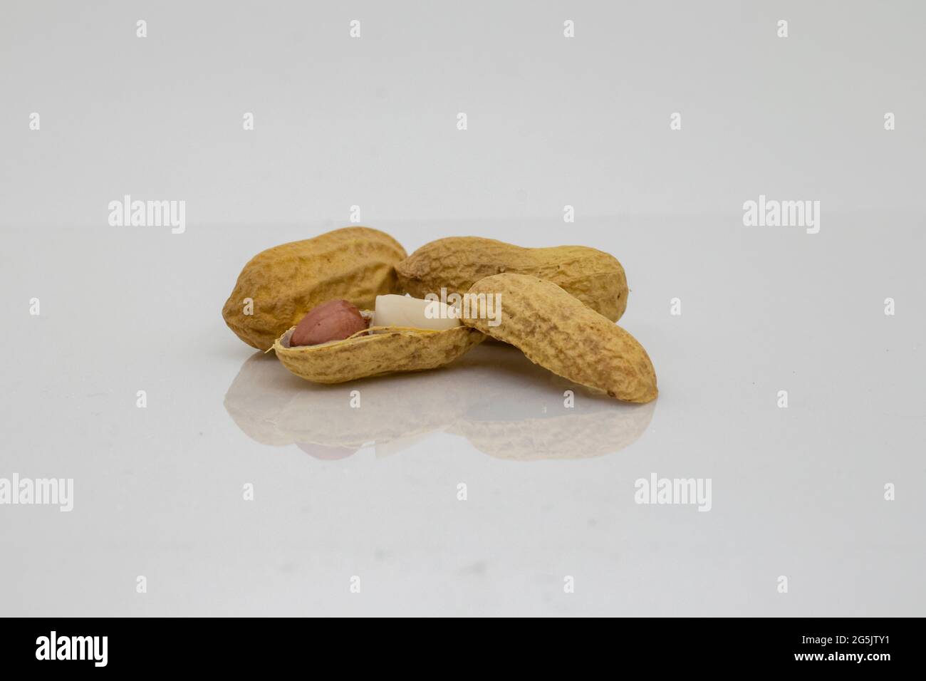 Arachides. Noix grillées isolées sur fond blanc avec surface réfléchissante. Banque D'Images