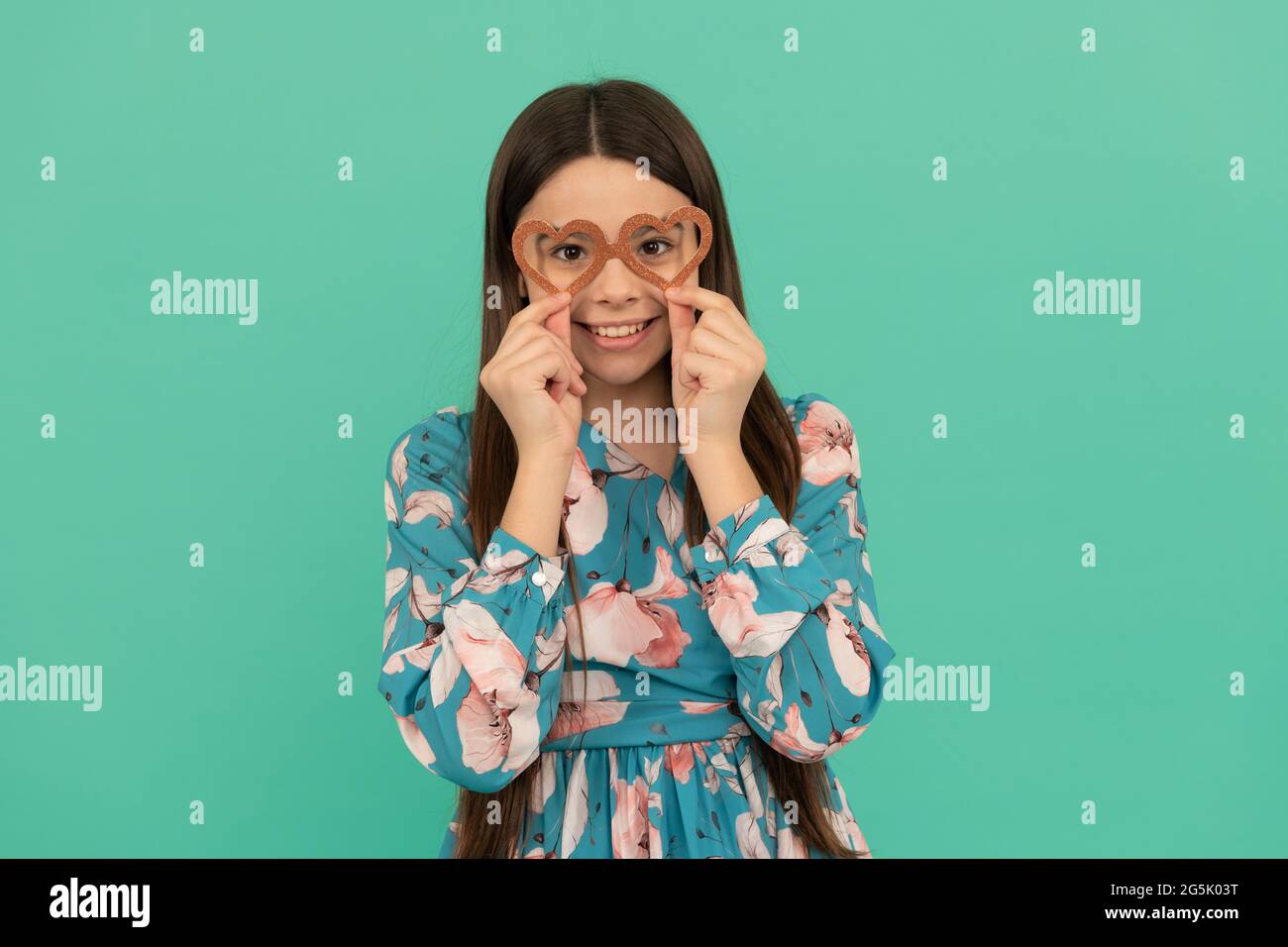 Bonne fille enfant sourire portant des lunettes de soutien en forme de coeur pour la Saint Valentin, Valentin. Banque D'Images