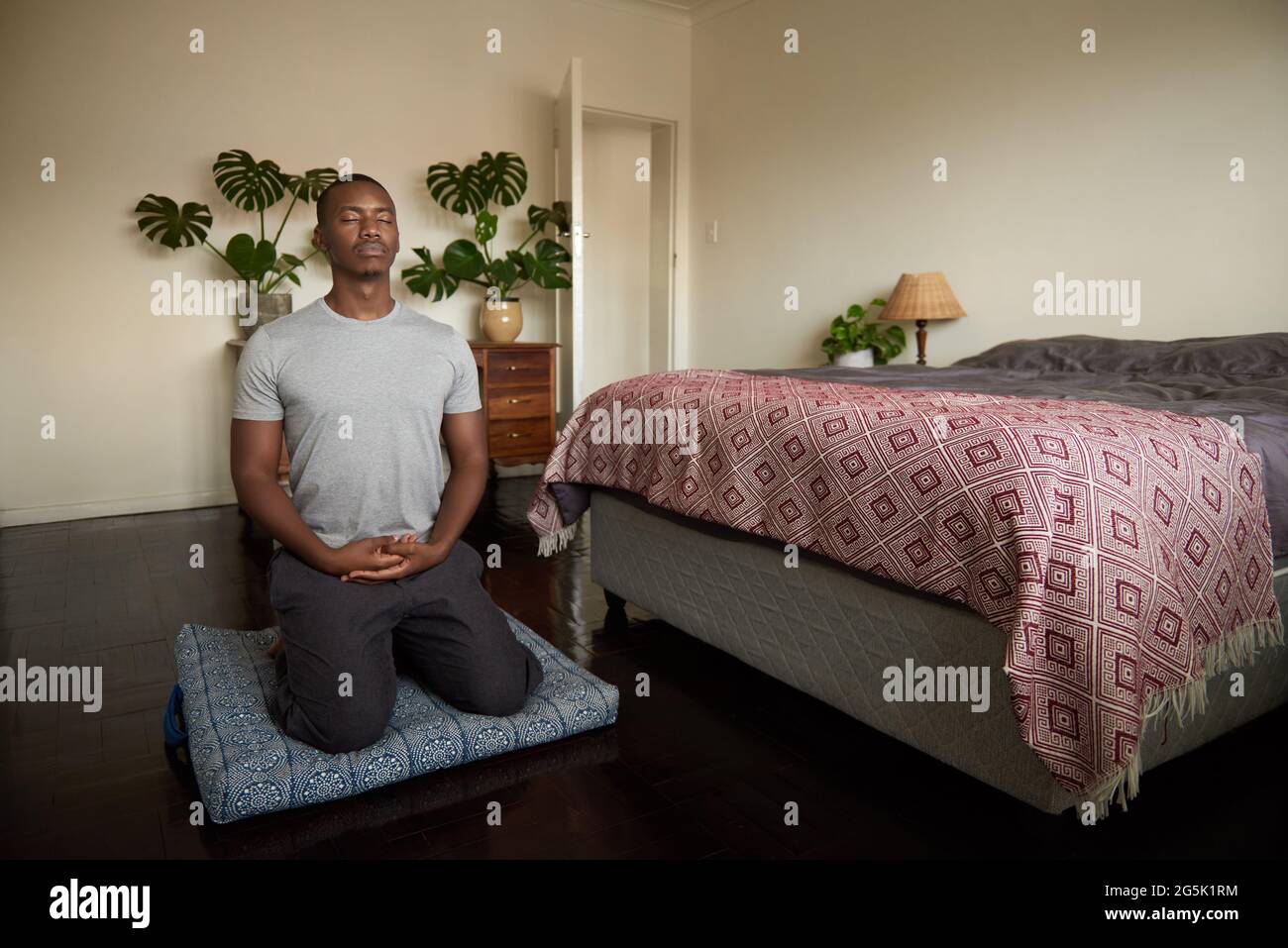 Jeune homme africain méditant sur le sol de sa chambre Banque D'Images