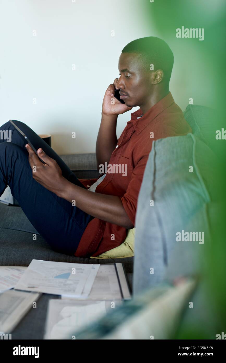Homme africain parlant au téléphone tout en travaillant à la maison Banque D'Images